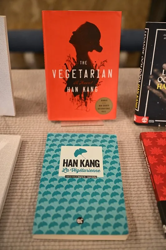 ในภาพนี้เป็นปกของนวนิยายเรื่อง The Vegetarian ในภาษาอังกฤษ (ปกสีส้ม) กับภาษาฝรั่งเศส (ปกสีฟ้า)